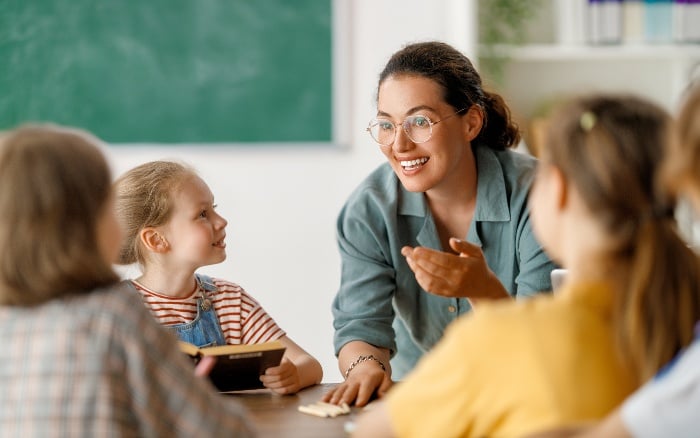 A teacher is talking to a group of children in a classroom.